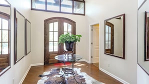 A hallway with a glass table, a potted plant, a cowhide rug, and a wooden door. - 18 Mi to Dtwn Memphis: Oasis on 8 Acres! (Southaven)