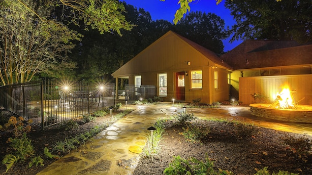 A well-lit wooden house with a stone pathway, a fenced garden, and a fire pit. - 18 Mi to Dtwn Memphis: Oasis on 8 Acres! (Southaven)