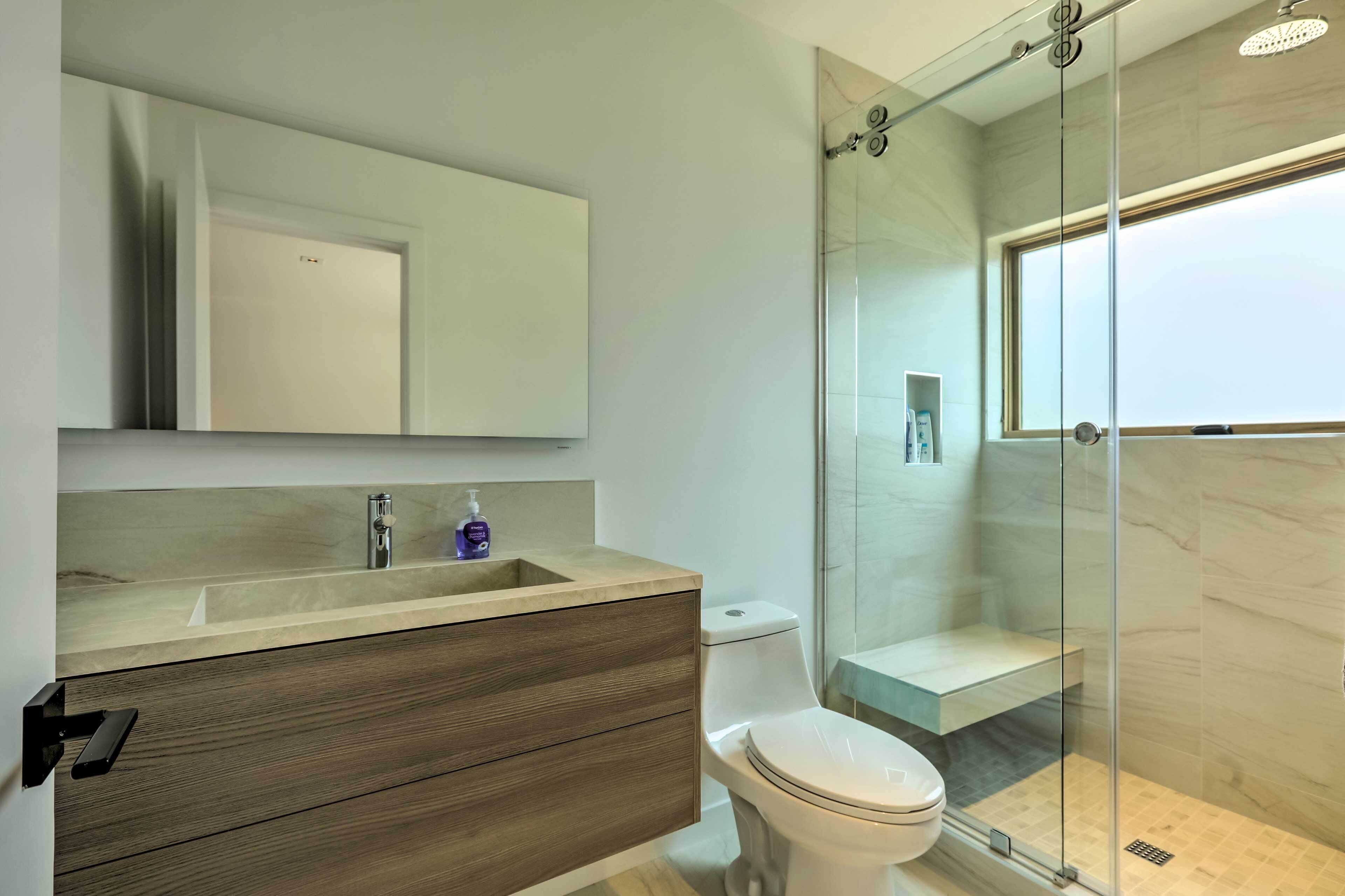 Een moderne badkamer met een douchecabine van glas, een houten wastafelmeubel en een grote spiegel.