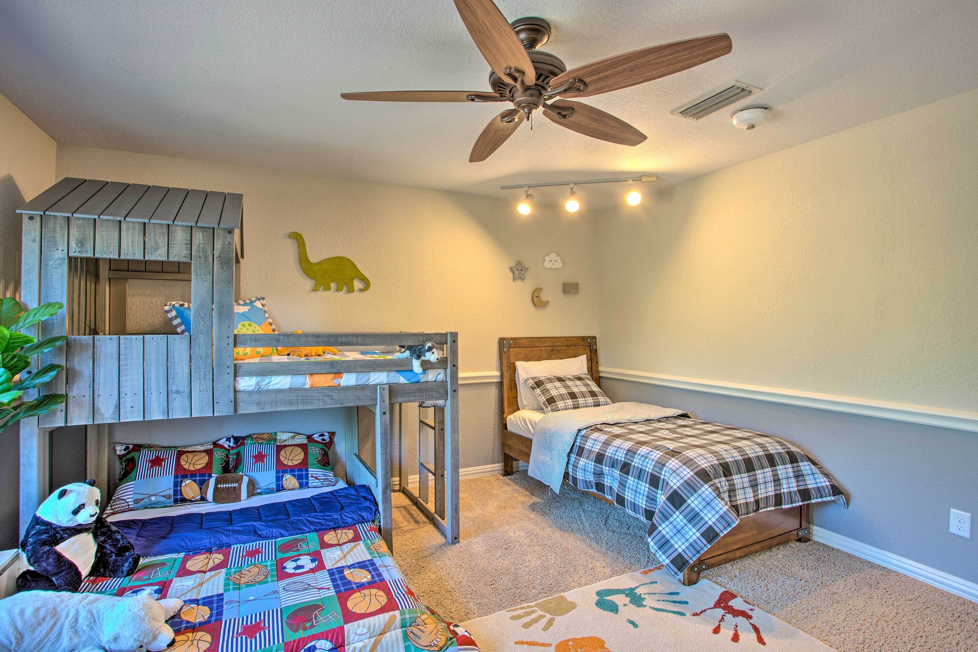 A child's bedroom with bunk beds, a ceiling fan, and wall decorations including a dinosaur and clouds.
