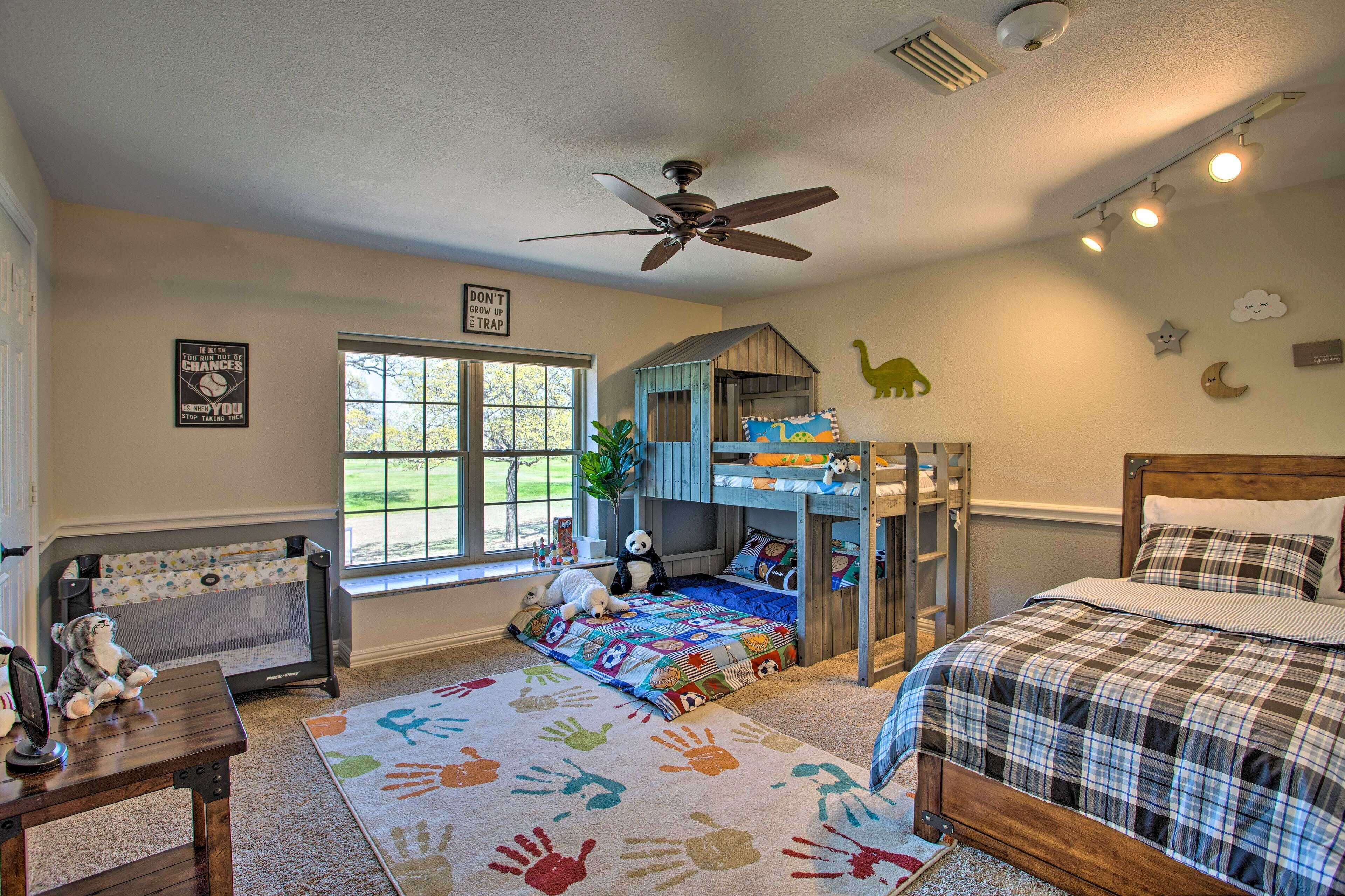 A child's bedroom with bunk beds, a ceiling fan, a window with a view, and a motivational poster on the wall.