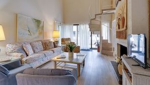 Un salon spacieux comprenant un canapé, des fauteuils, une table basse et une cheminée.