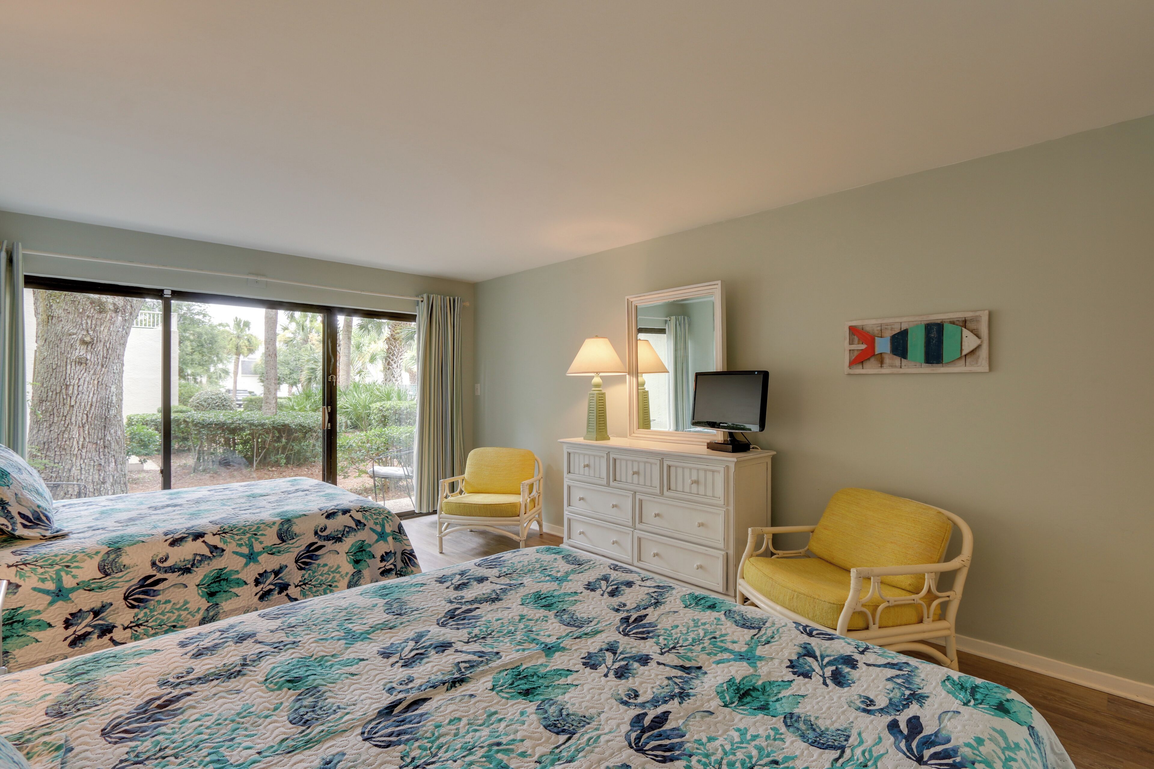 A hotel room with two beds, a dresser, a television, and a chair.