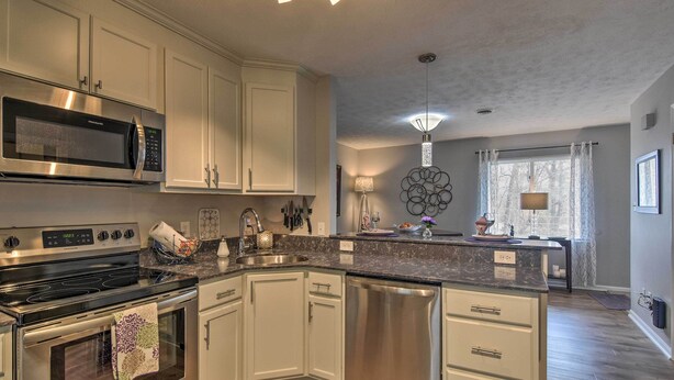 A modern kitchen with white cabinetry, stainless steel appliances, and a granite countertop. - Condo w/ Sunroom, Near Downtown Hendersonville! (Hendersonville)