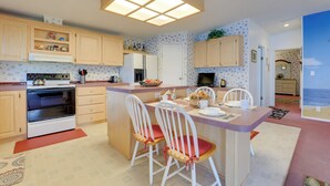 A kitchen with wooden cabinets, a central island with chairs, a refrigerator, and a stove. - Steps to Pool: Winter Garden House w/ Lanai! (Winter Garden)