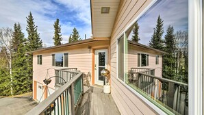 Une maison à deux étages avec un balcon, de grandes fenêtres et une vue sur les arbres.