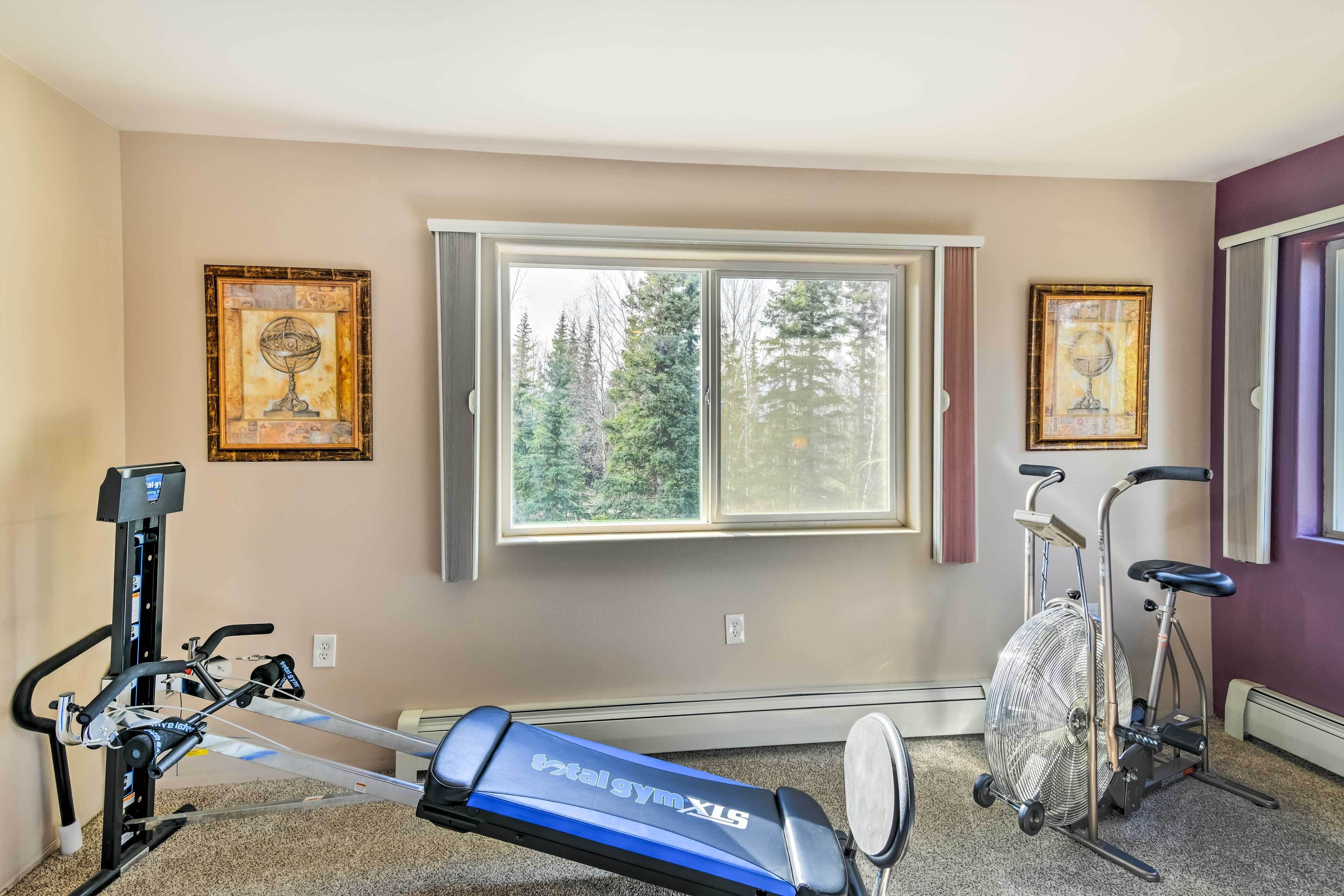 A home gym with a stationary bike, elliptical, and fan.