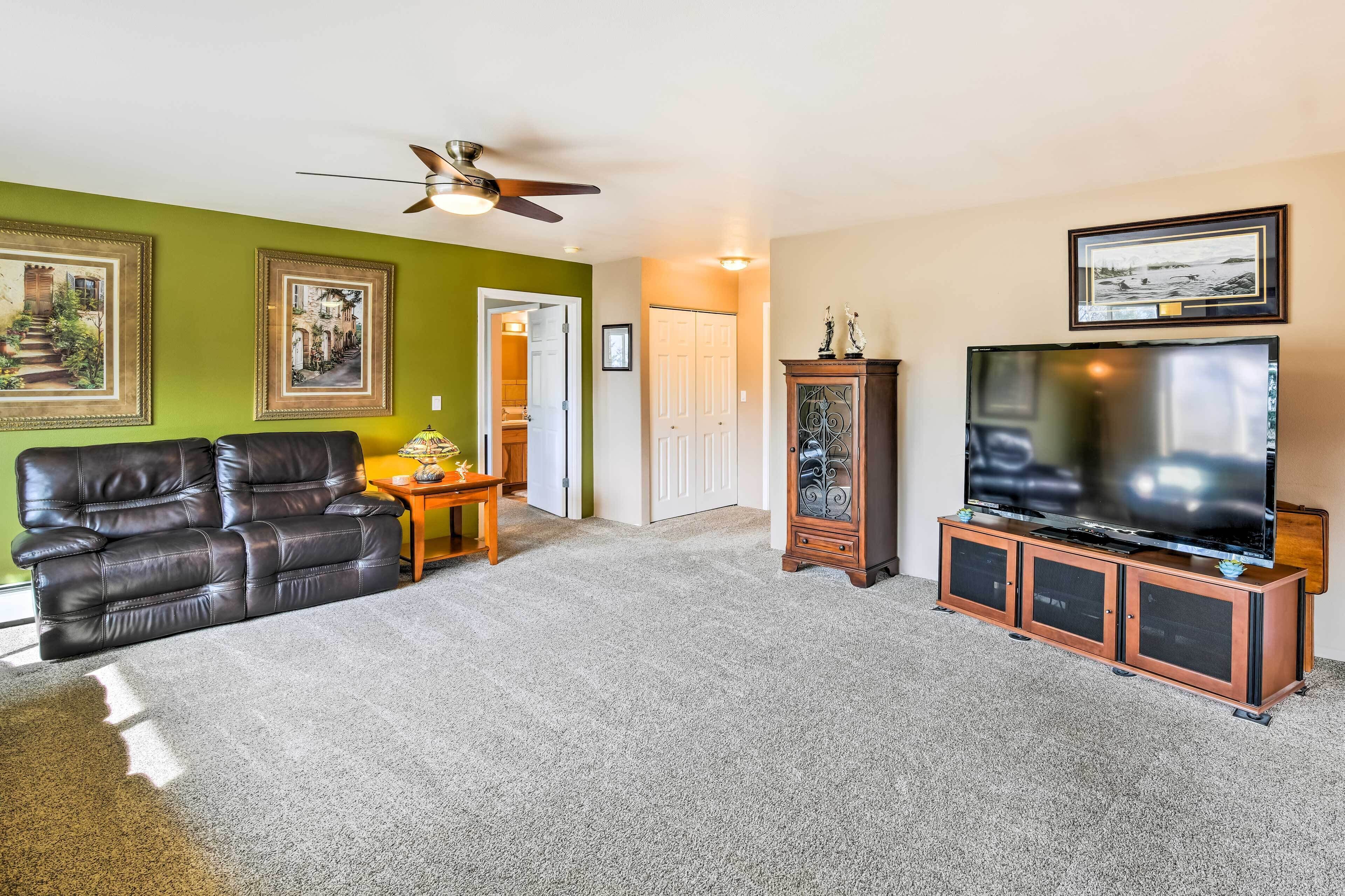 A living room with a leather sofa, a TV on a cabinet, and framed pictures on the wall.