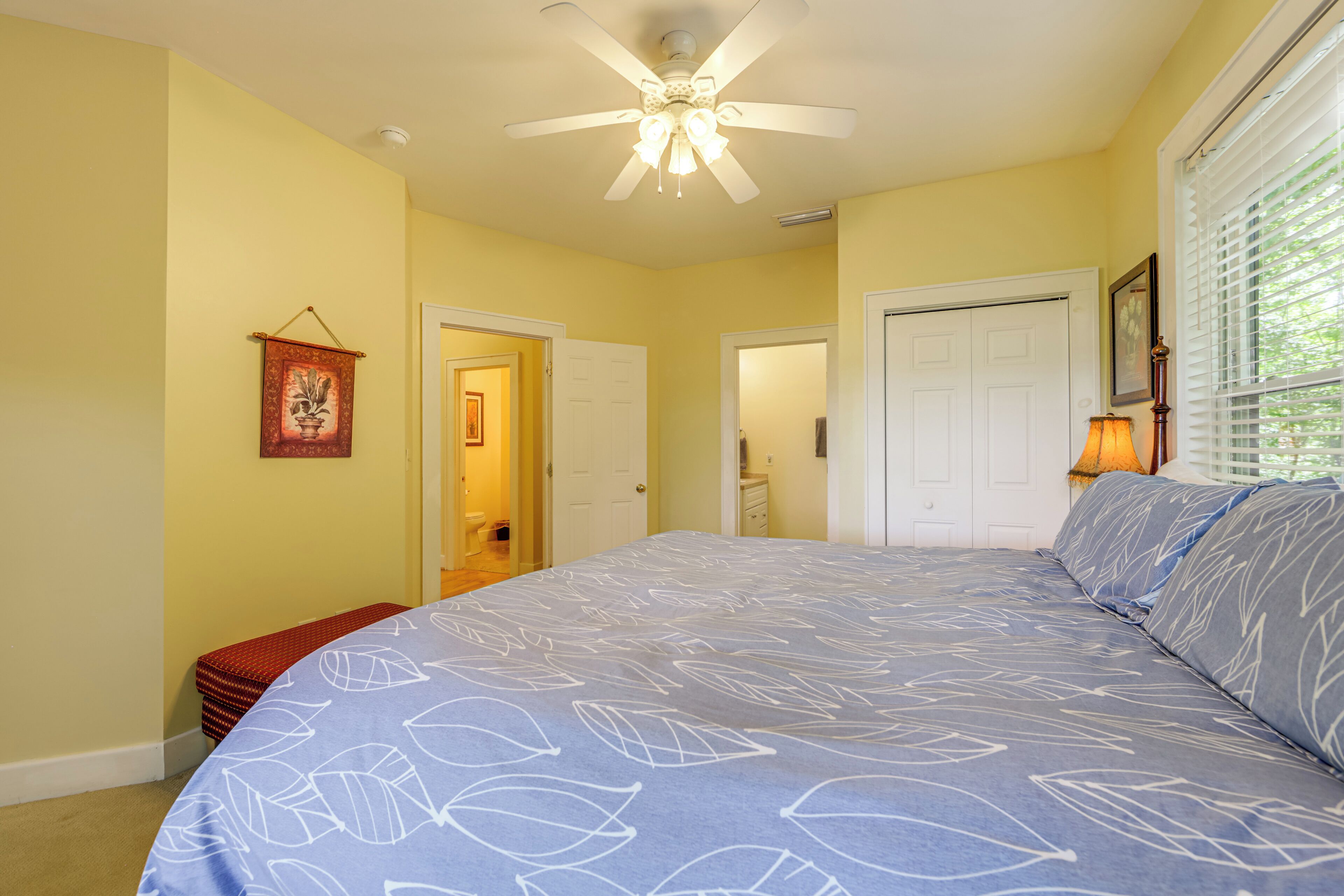 A bedroom with a bed, a ceiling fan, and a window with blinds.