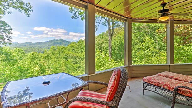 A covered outdoor seating area with a table and chairs, overlooking a forested landscape. - Mountain View Home: Hike, Raft, Golf + More! (Bryson City)