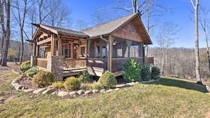 A wooden cabin with a porch and stone foundation, surrounded by trees and a well-maintained lawn. - Pet-friendly Cabin w/ Mtn Views in Chinquapin! (Glenville)