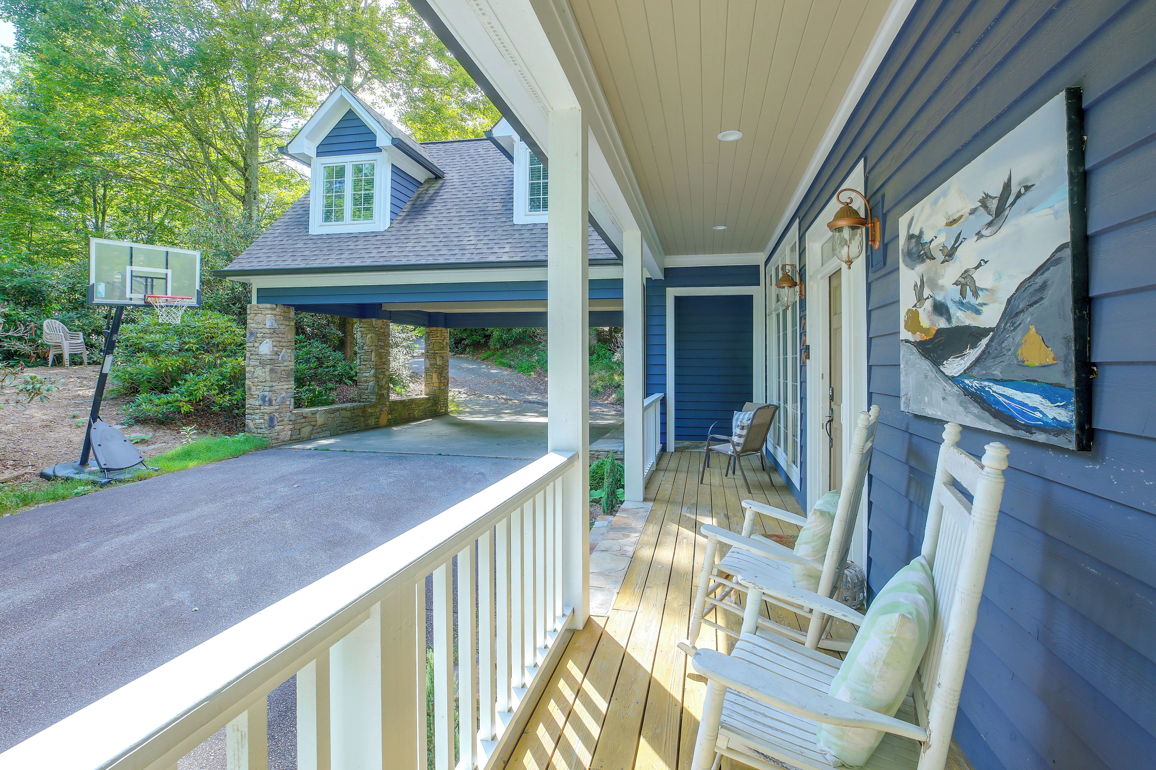 A covered porch with a basketball hoop, stone pillars, and a painting of birds.