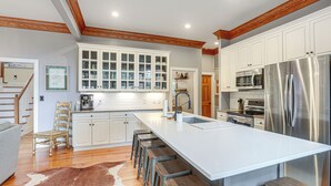 Una cocina moderna con armarios blancos, electrodomésticos de acero inoxidable y una isla grande con taburetes de bar.