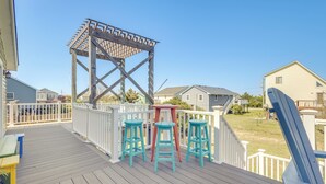 Une terrasse en bois avec une pergola, trois tabourets et un banc.