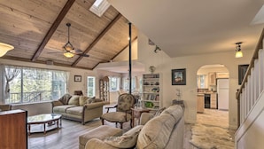 A spacious living room with a high ceiling, wooden beams, and a view of the kitchen through an archway. - 20 Mi to Lassen Park: Chateau w/ Mt Shasta View! (Shingletown)