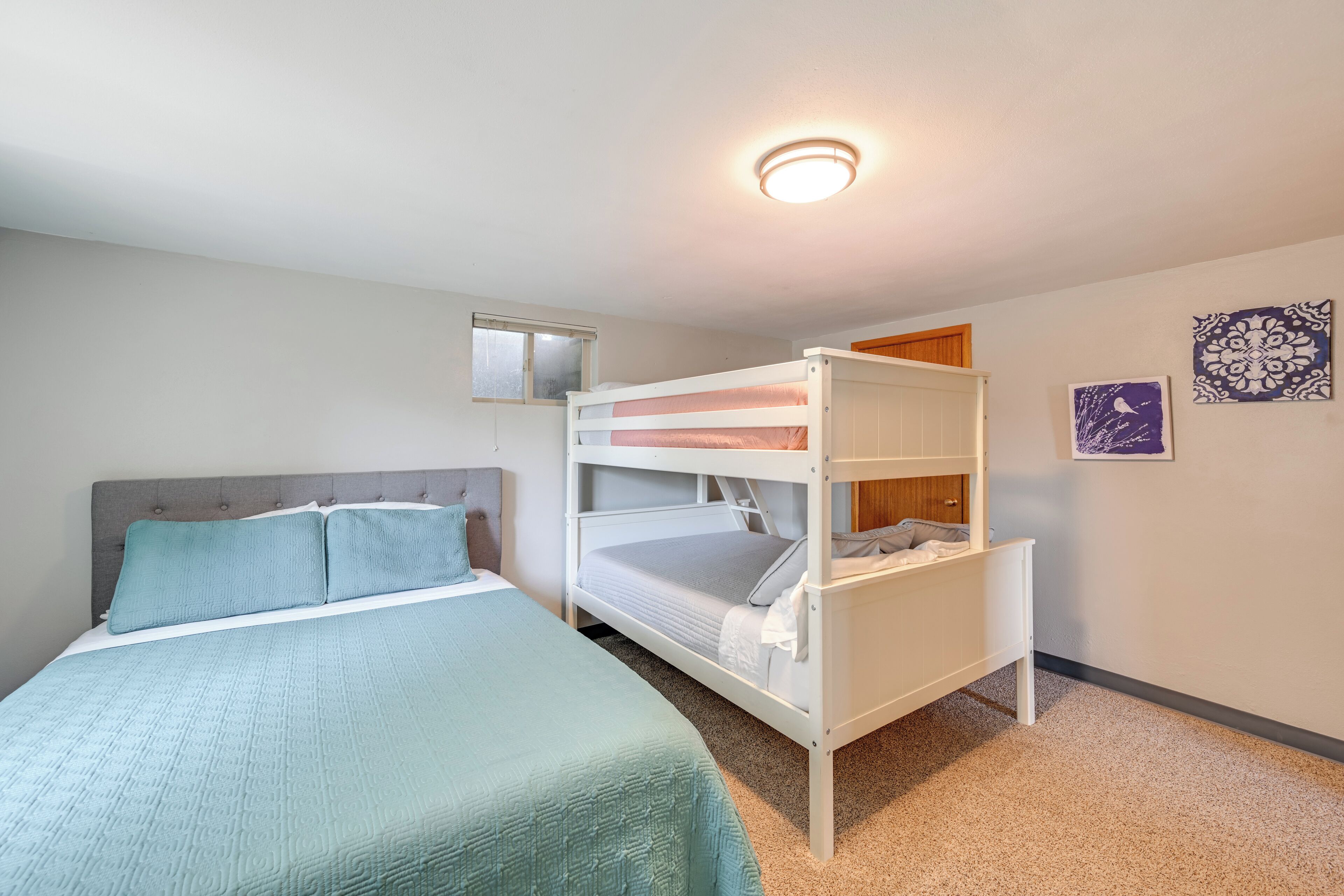 A room with a single bed, a bunk bed, a window, and a wall with two decorative plates.