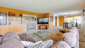 A living room with a sofa, a glass coffee table, a fireplace, a TV, and wooden shelves. - Family-friendly Yakima Escape w/ Yard & Pool! (Yakima)