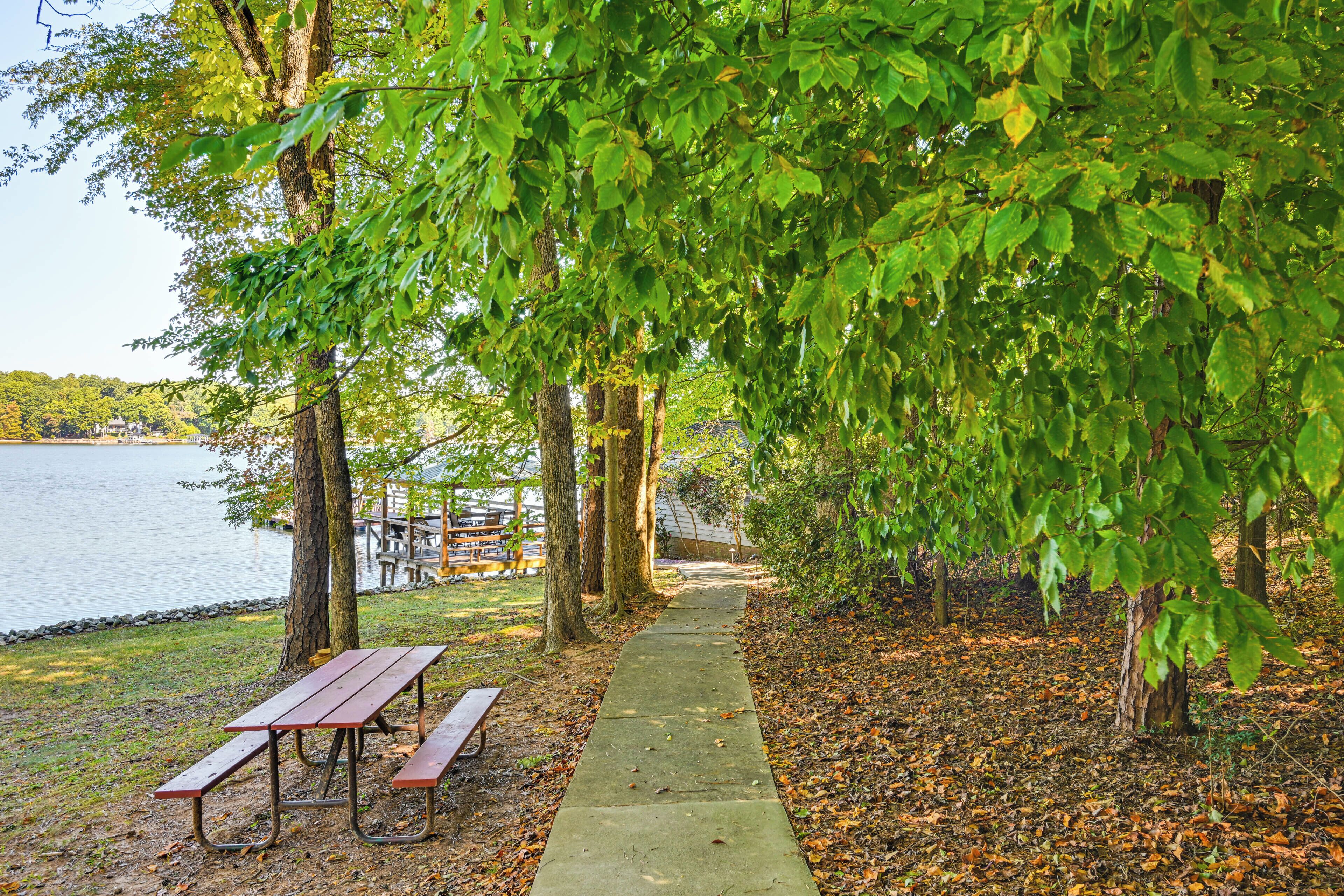 Un área de picnic junto al lago con bancos y un camino de hormigón.