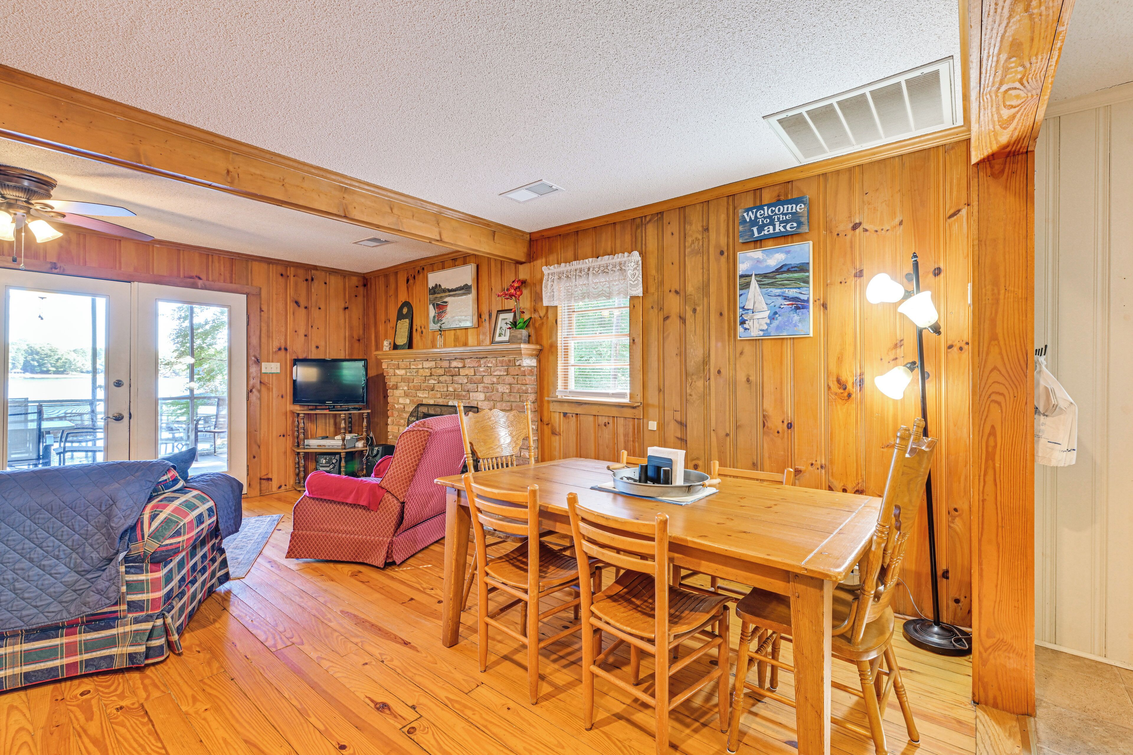 A cozy room with a wooden floor, a dining table with chairs, a sofa, a television, and a fireplace.