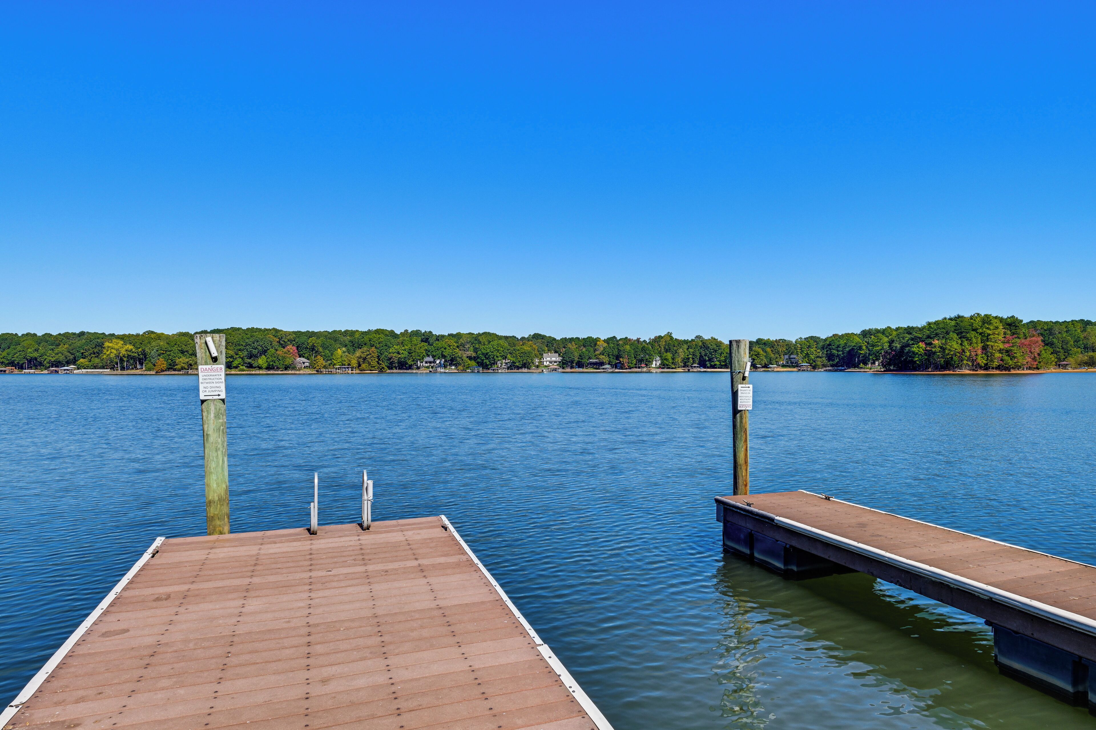 A wooden dock extending into calm water with a clear sky above.