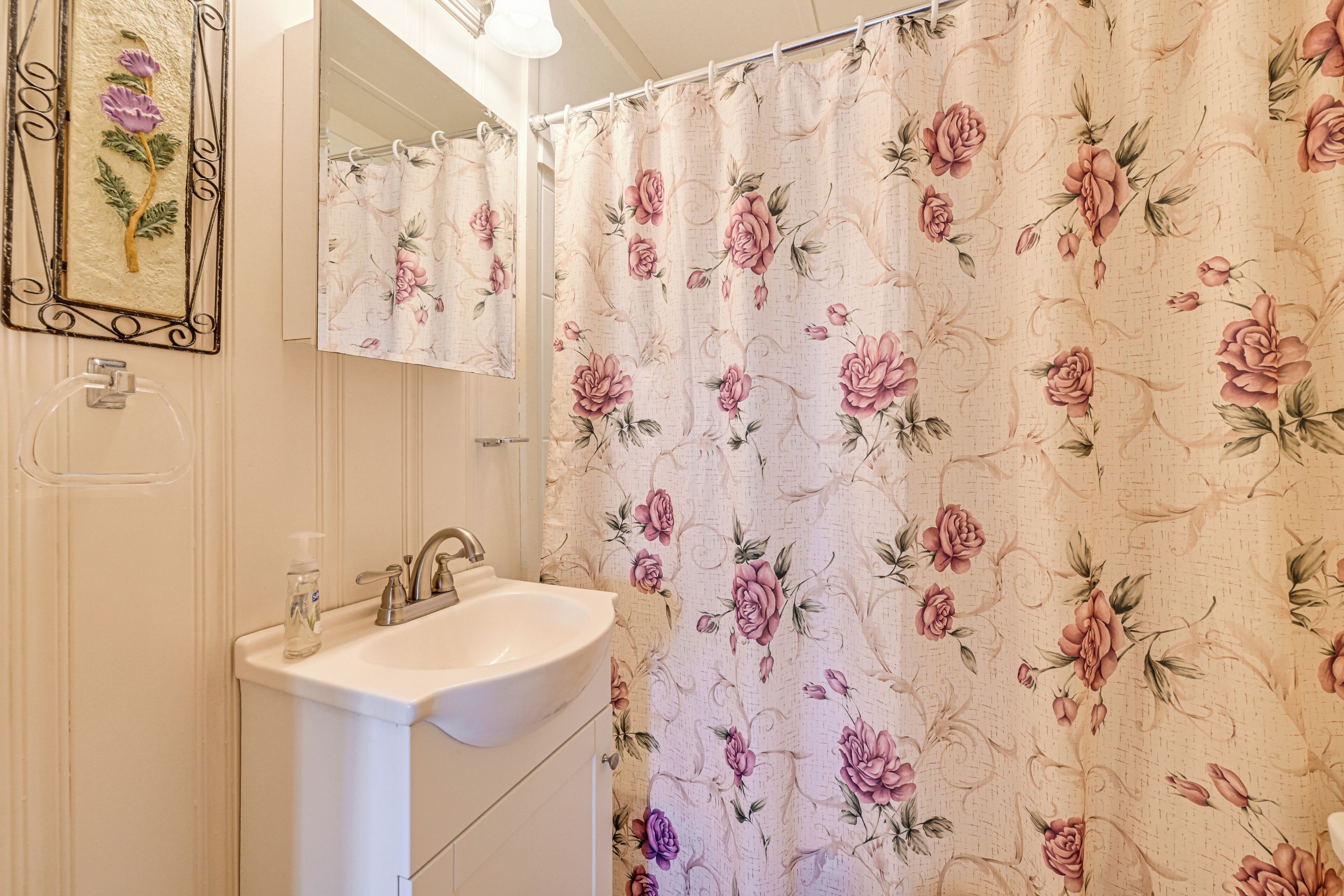 A bathroom with a white sink, a mirror, and a shower curtain with a floral pattern.