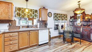 A kitchen with wooden cabinets, a dishwasher, a dining table with chairs, and a chandelier. - Mtn Gate Guest House ~ 6 Mi to Shasta Lake! (Redding)