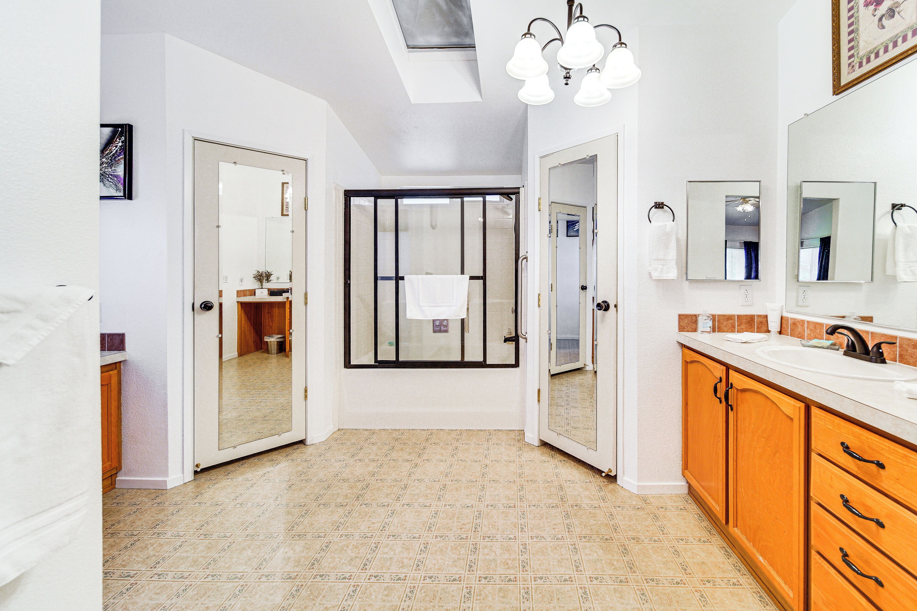 A modern bathroom with a shower, a large mirror, and a vanity with a sink.