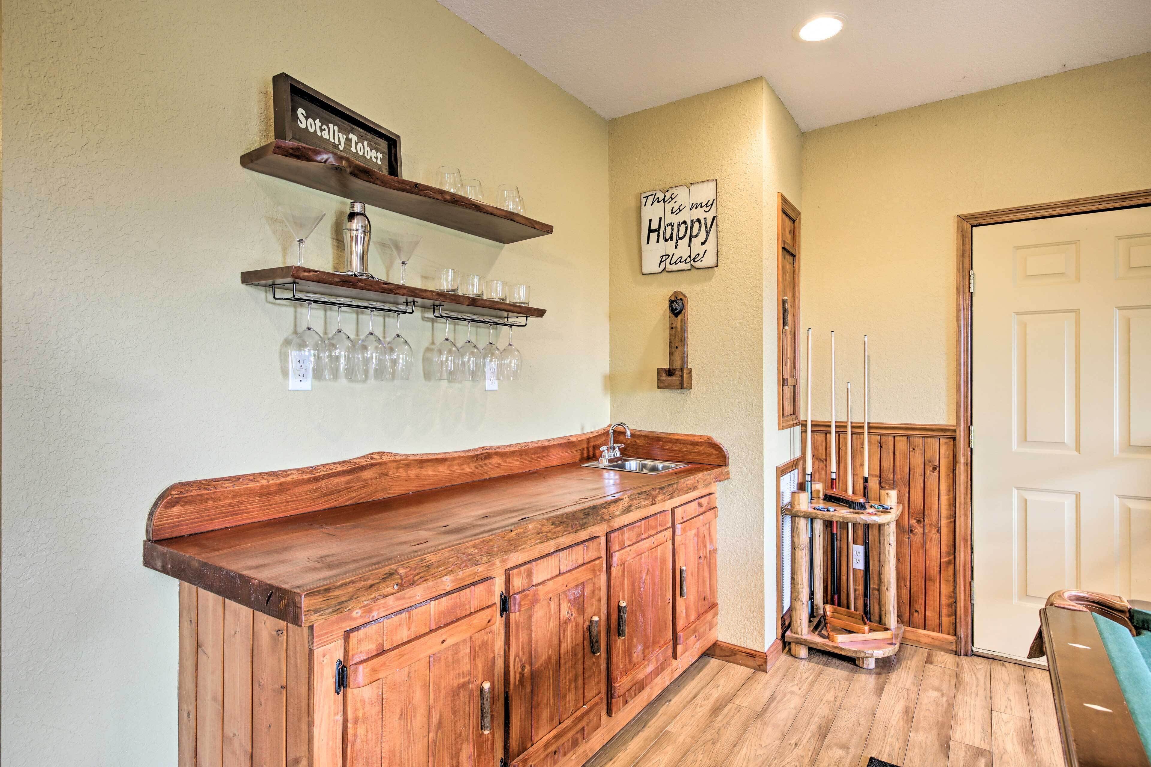 Un comptoir de bar en bois, avec des étagères au-dessus pour ranger les verres et une bouteille.