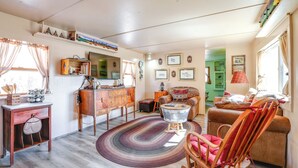 A cozy living room with a fireplace, wooden furniture, and a green door in the background. - Colorado Vacation Rental w/ Deck & Mtn Views (Cripple Creek)