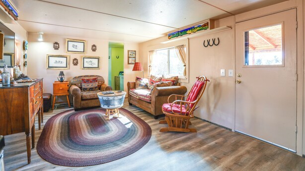 A cozy living room with a wooden floor, a patterned rug, a wooden chair, a sofa, and a small table. - Colorado Vacation Rental w/ Deck & Mtn Views (Cripple Creek)