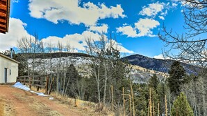 A rural landscape with a dirt path leading to a wooden fence, surrounded by trees and a mountain in the background. - Colorado Vacation Rental w/ Deck & Mtn Views (Cripple Creek)