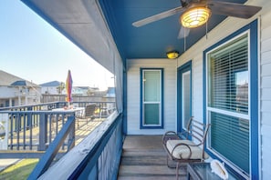 A balcony with a ceiling fan, a table with chairs, and a view of neighboring houses.