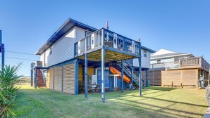 Ein zweistöckiges Haus mit Balkon, Treppe und einer Rutsche, die zum oberen Stockwerk führt.