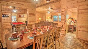 A wooden interior with a dining table set for a meal, a pool table, and ceiling fans. - Broken Bow Oasis: Hot Tub, Fire Pit & Patio (Broken Bow)