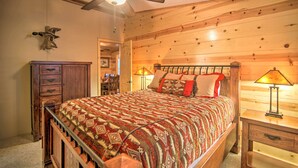 A wooden-paneled bedroom with a bed, nightstands, a dresser, and a ceiling fan. - Broken Bow Oasis: Hot Tub, Fire Pit & Patio (Broken Bow)