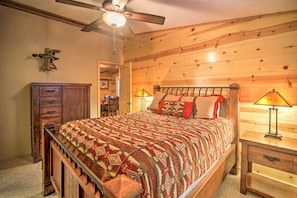 A wooden-paneled bedroom with a bed, nightstands, a dresser, and a ceiling fan. - Broken Bow Oasis: Hot Tub, Fire Pit & Patio (Broken Bow)