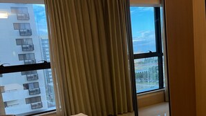 Habitación de hotel con un ventanal grande, una cama, una silla y un espejo.