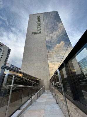 Un edificio alto con fachada de vidrio y una escalera que conduce hacia él.