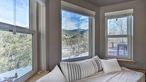 Une chambre dotée d’une grande fenêtre donnant sur un paysage enneigé et des montagnes.