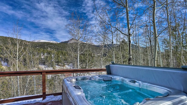 Un bain à remous sur une terrasse en bois avec vue sur les montagnes.