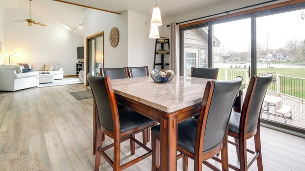 A dining area with a large table and chairs, a ceiling fan, and a view of the outdoors. - Cadillac Vacation Rental w/ Dock on Lake Mitchell! (Cadillac)