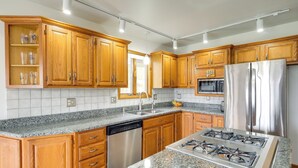 A kitchen with wooden cabinets, a stainless steel refrigerator, a dishwasher, and a gas stove. - Cadillac Vacation Rental w/ Dock on Lake Mitchell! (Cadillac)