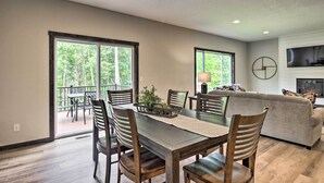 A spacious living area with a dining table, chairs, and a sofa. There is a fireplace and a television mounted on the wall. - Upscale Townhome in Causeways on Gull Resort! (Nisswa)