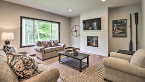 A living room with a sofa, coffee table, and a fireplace. - Upscale Townhome in Causeways on Gull Resort! (Nisswa)