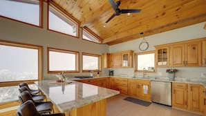 A spacious kitchen with wooden cabinets, a large island with bar stools, and a ceiling fan. - Views & Hot Tub! Beech Mtn 'sky Barn Retreat' (Banner Elk)