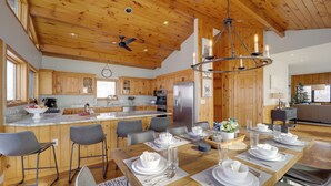 A spacious kitchen with wooden cabinets, a large island, and modern appliances. - Views & Hot Tub! Beech Mtn 'sky Barn Retreat' (Banner Elk)