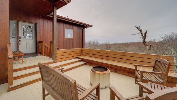 A wooden deck with a bench and chairs, a fire pit, and a door leading to a building. - Views & Hot Tub! Beech Mtn 'sky Barn Retreat' (Banner Elk)