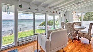 A spacious room with large windows overlooking a body of water, a round table, and wicker chairs. - Waterfront Portsmouth Cottage: 8 Mi. From Newport! (Portsmouth)