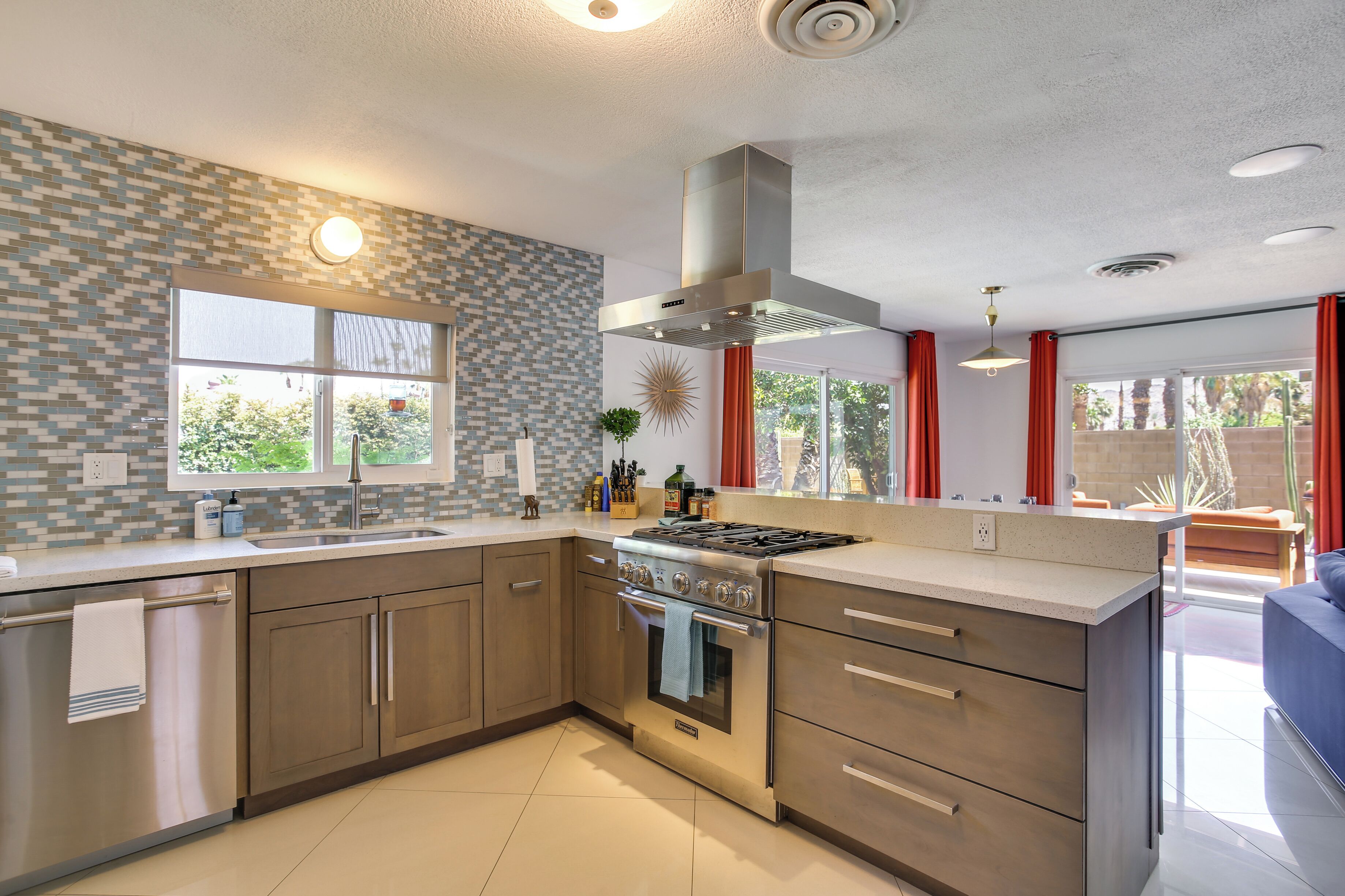 Een moderne keuken met een groot eiland, roestvrijstalen apparatuur en uitzicht op de omgeving.