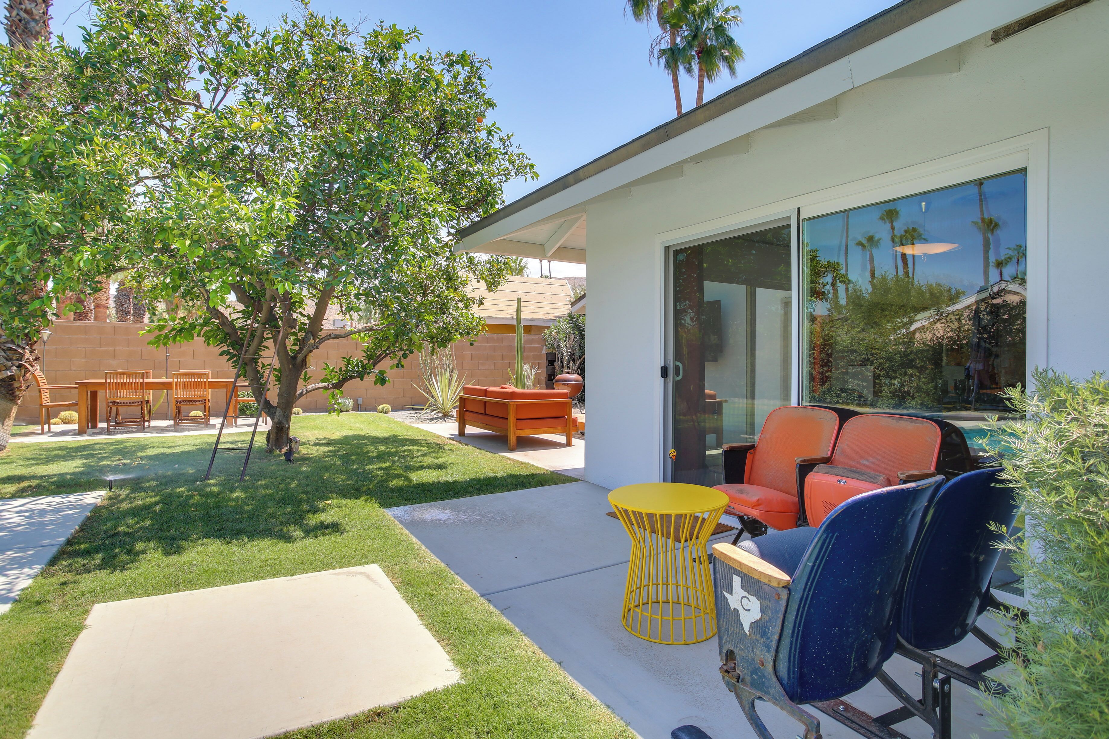 A patio with outdoor furniture, a tree, and a building with large windows.